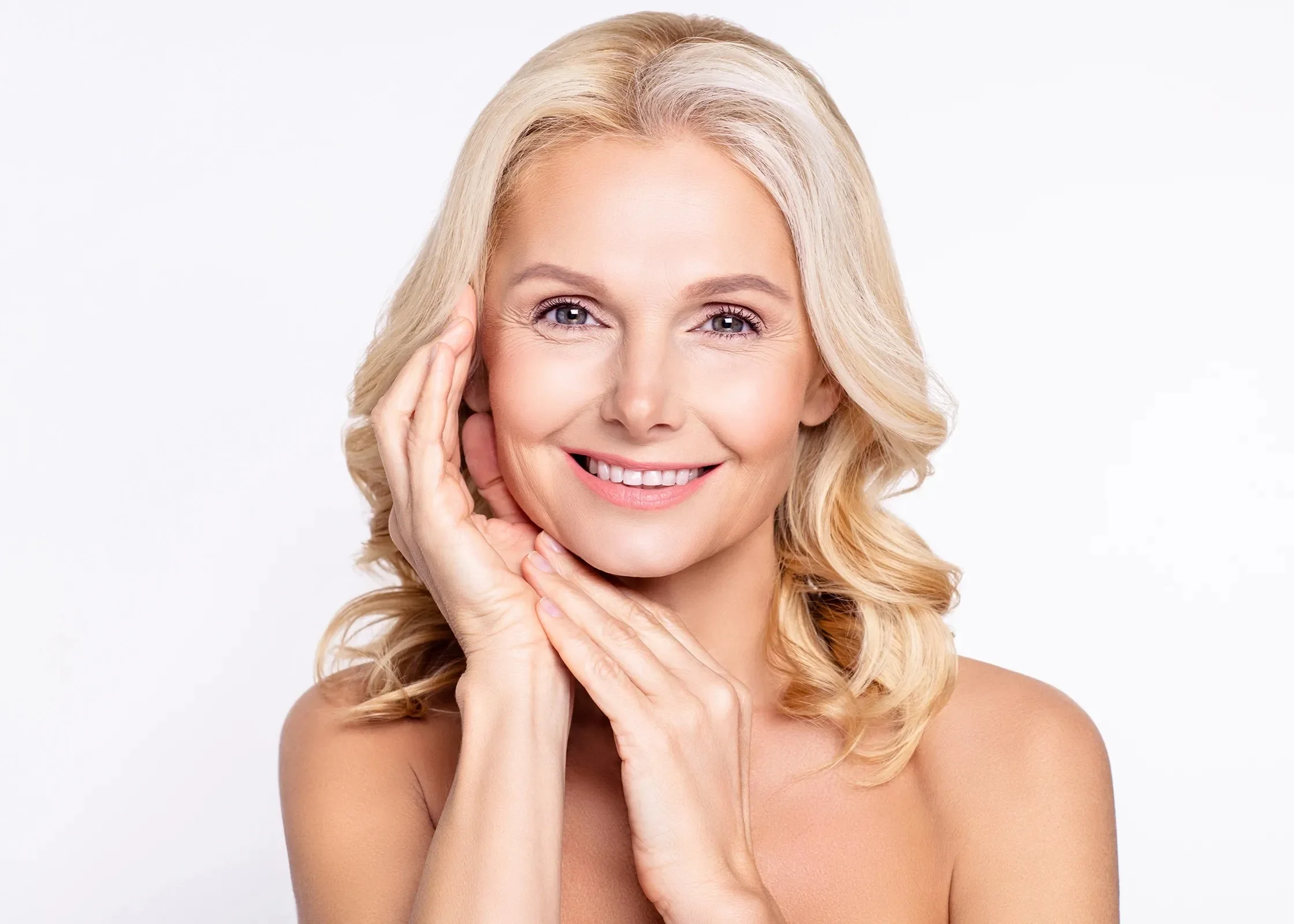 Smiling blonde woman with her hands beside her face.
