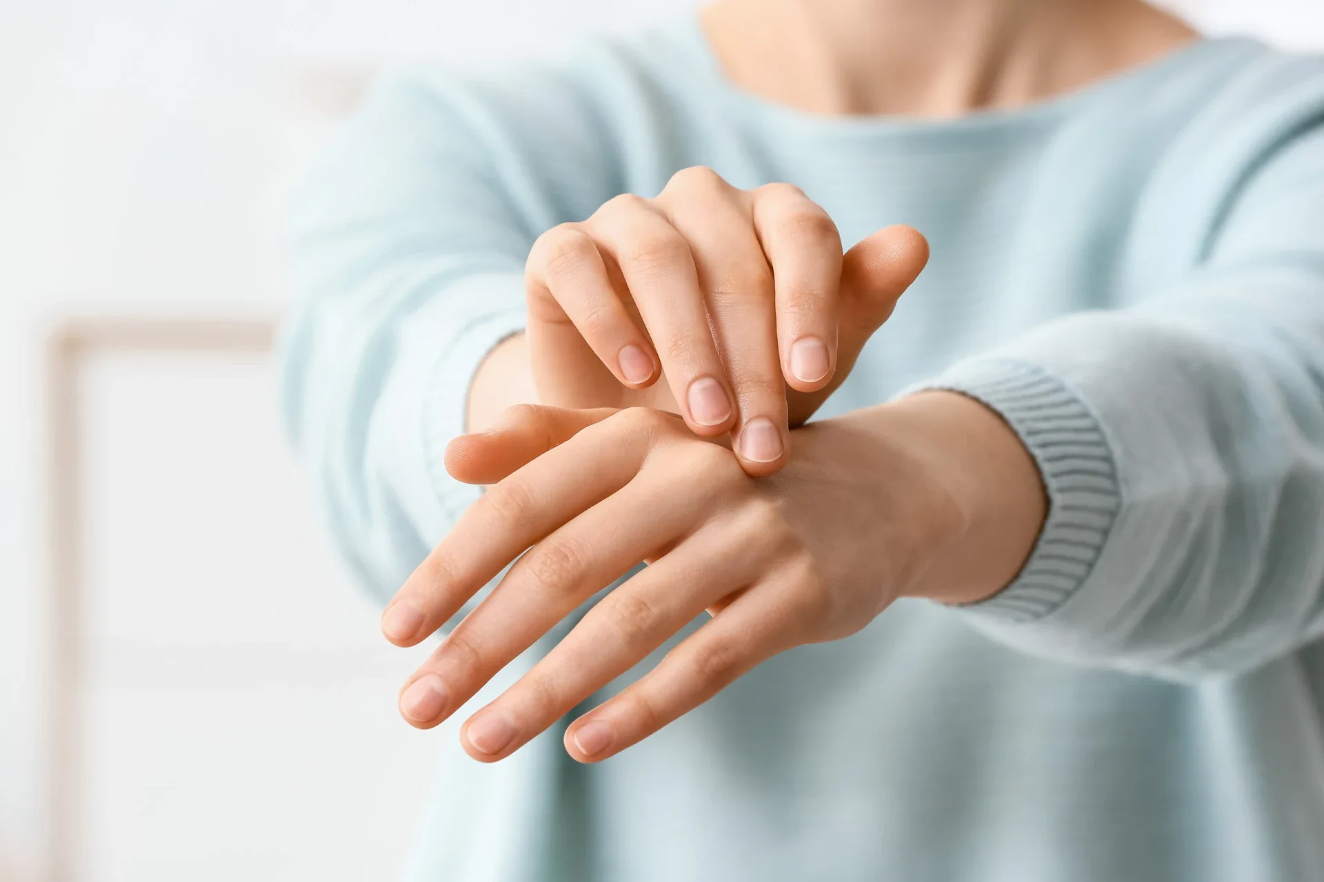 Person gently rubbing the back of one hand.
