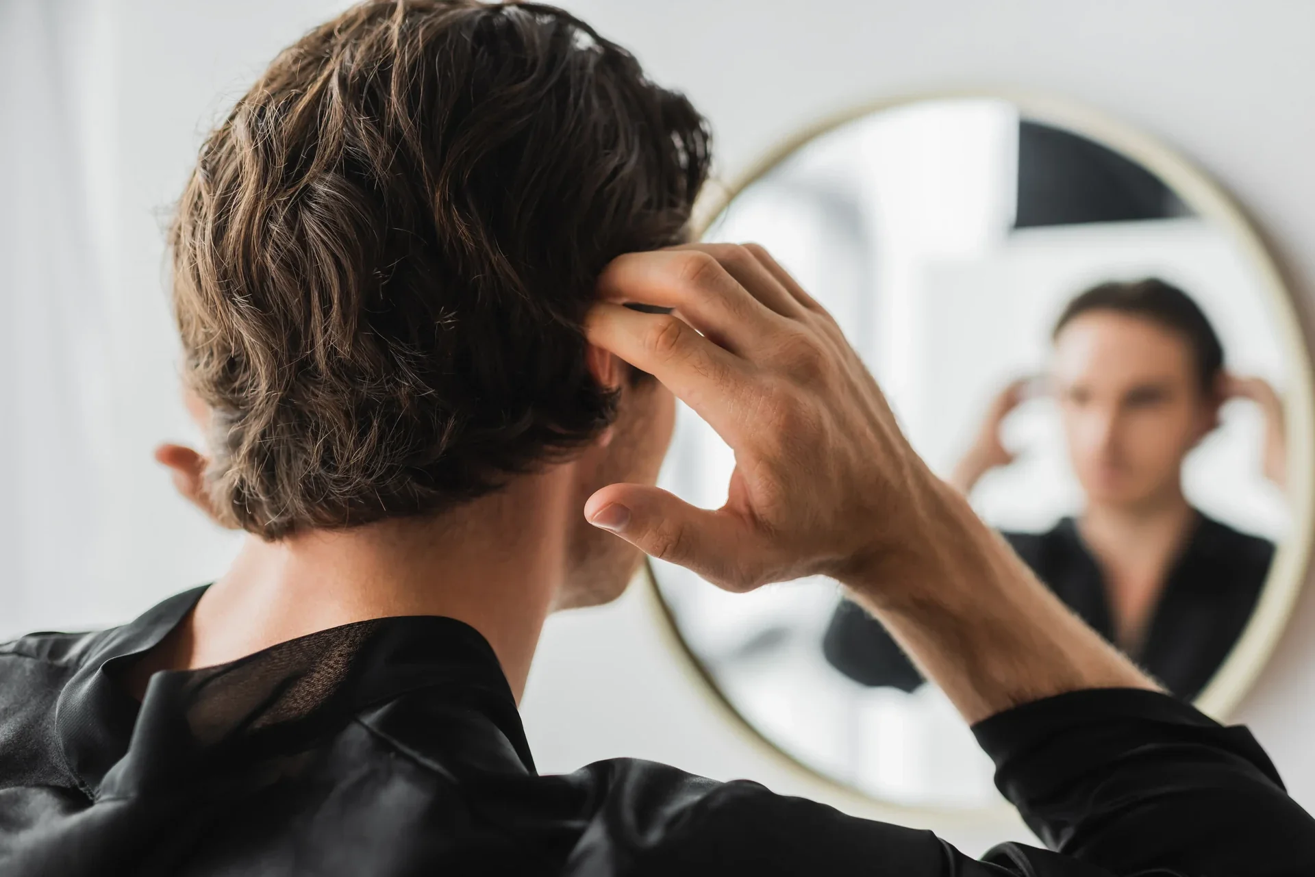 Man checking his hair in a mirror.