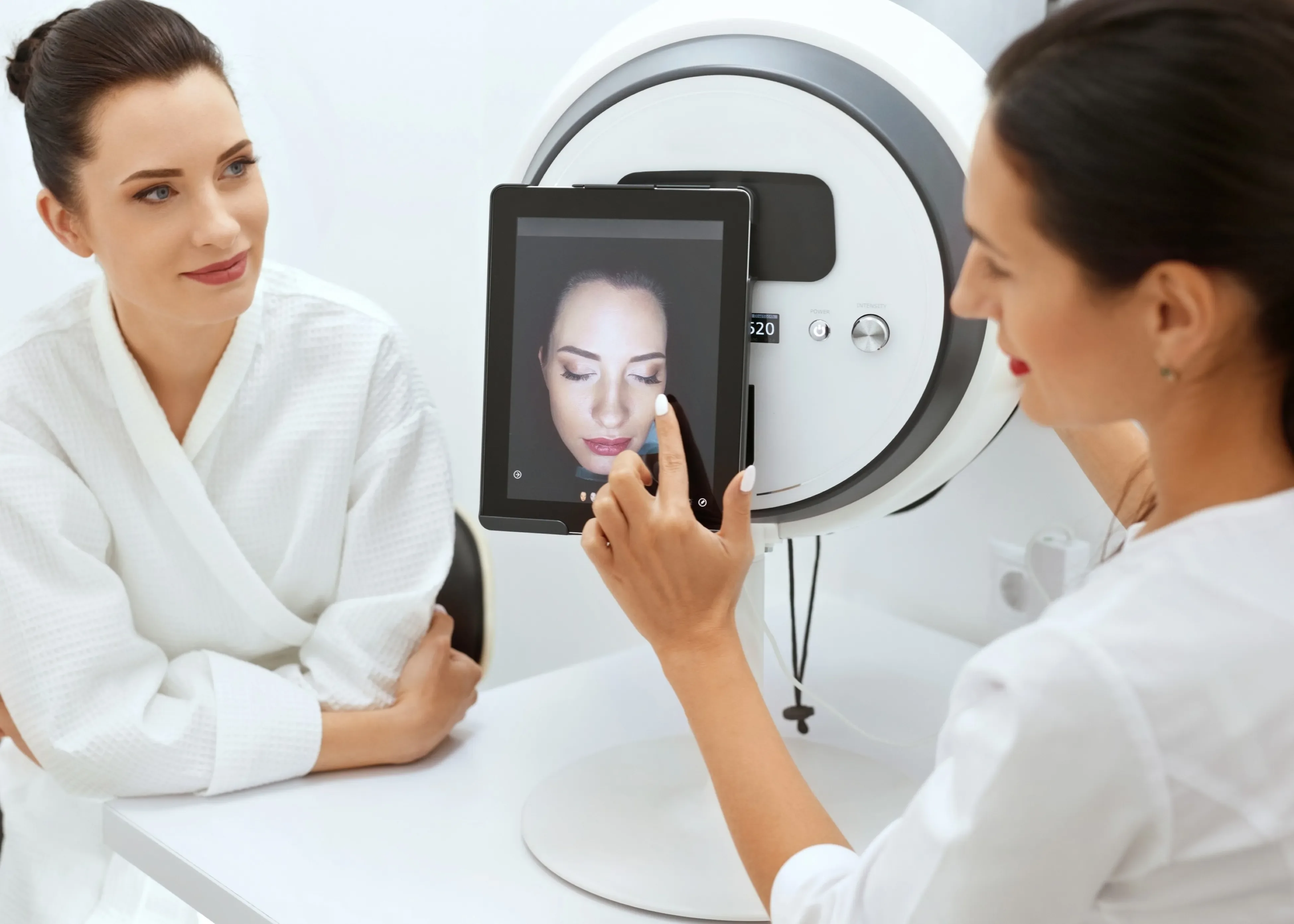 Practitioner and client reviewing images on a skin analysis device.