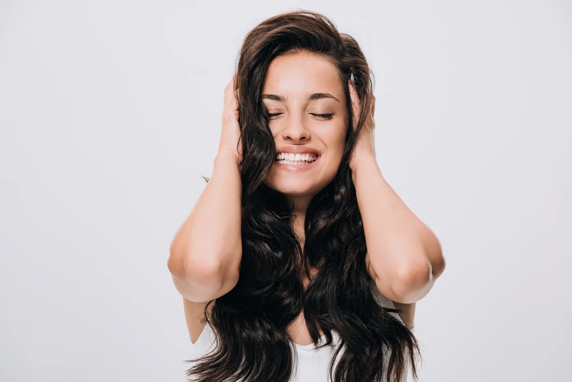 Woman smiling with her hands in her hair.