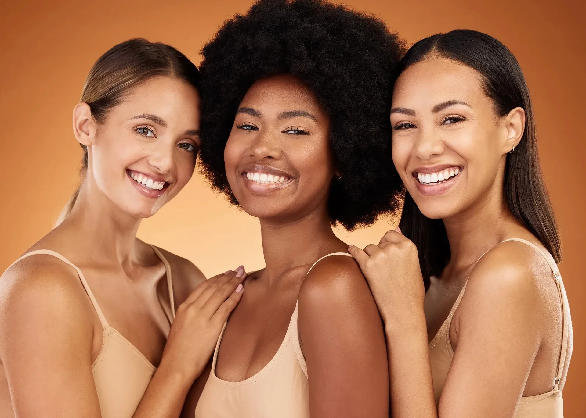 Three smiling women posing together.