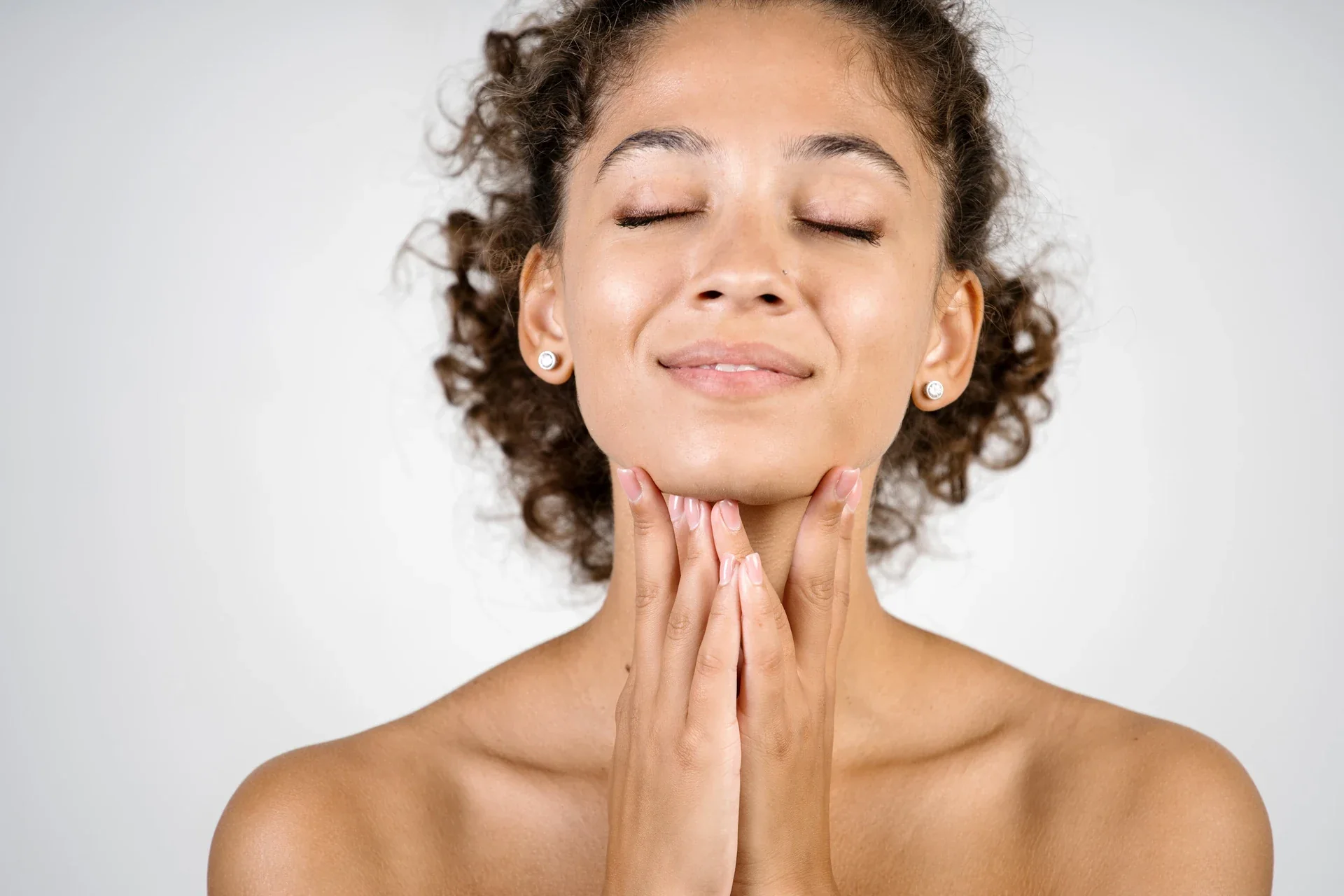 Woman gently touching her neck with her eyes closed.