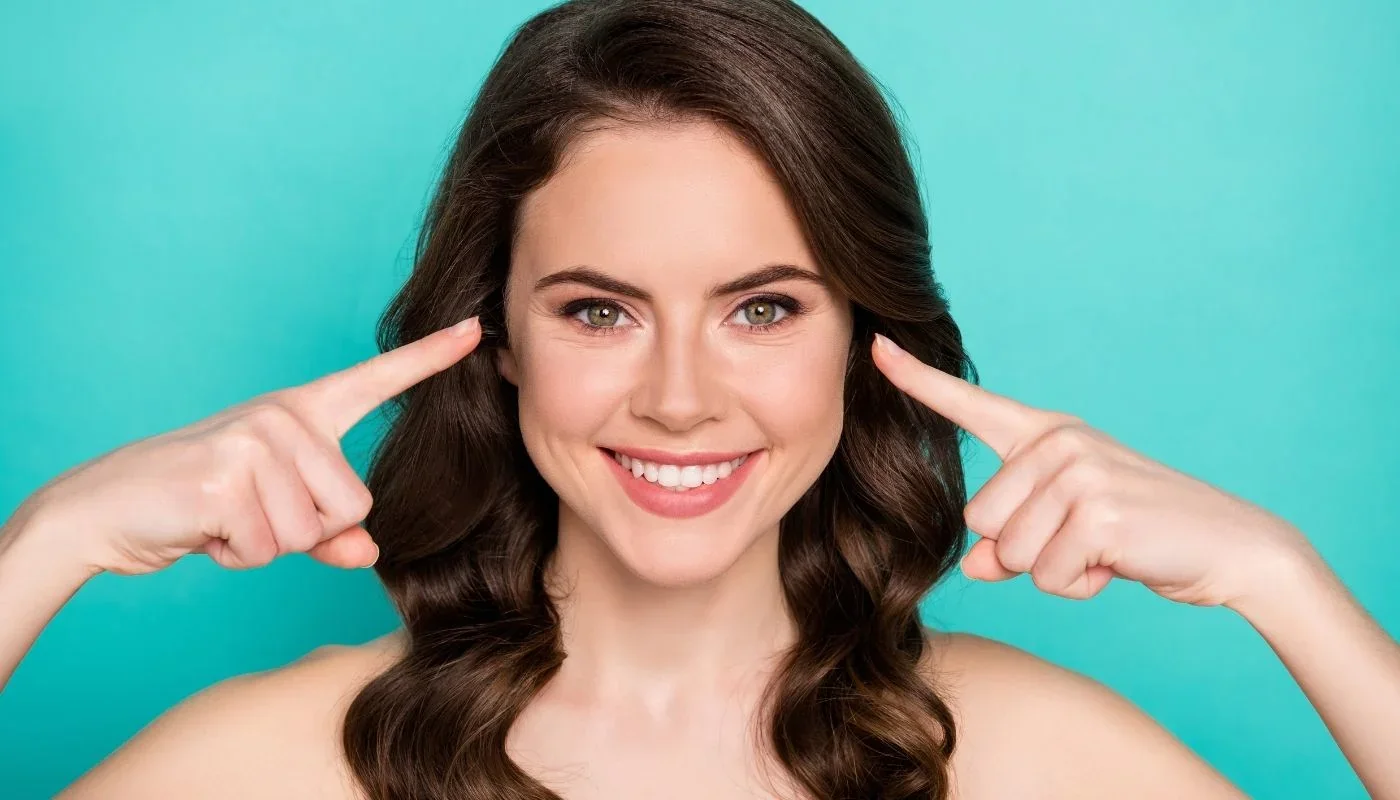 Woman pointing to her cheeks.