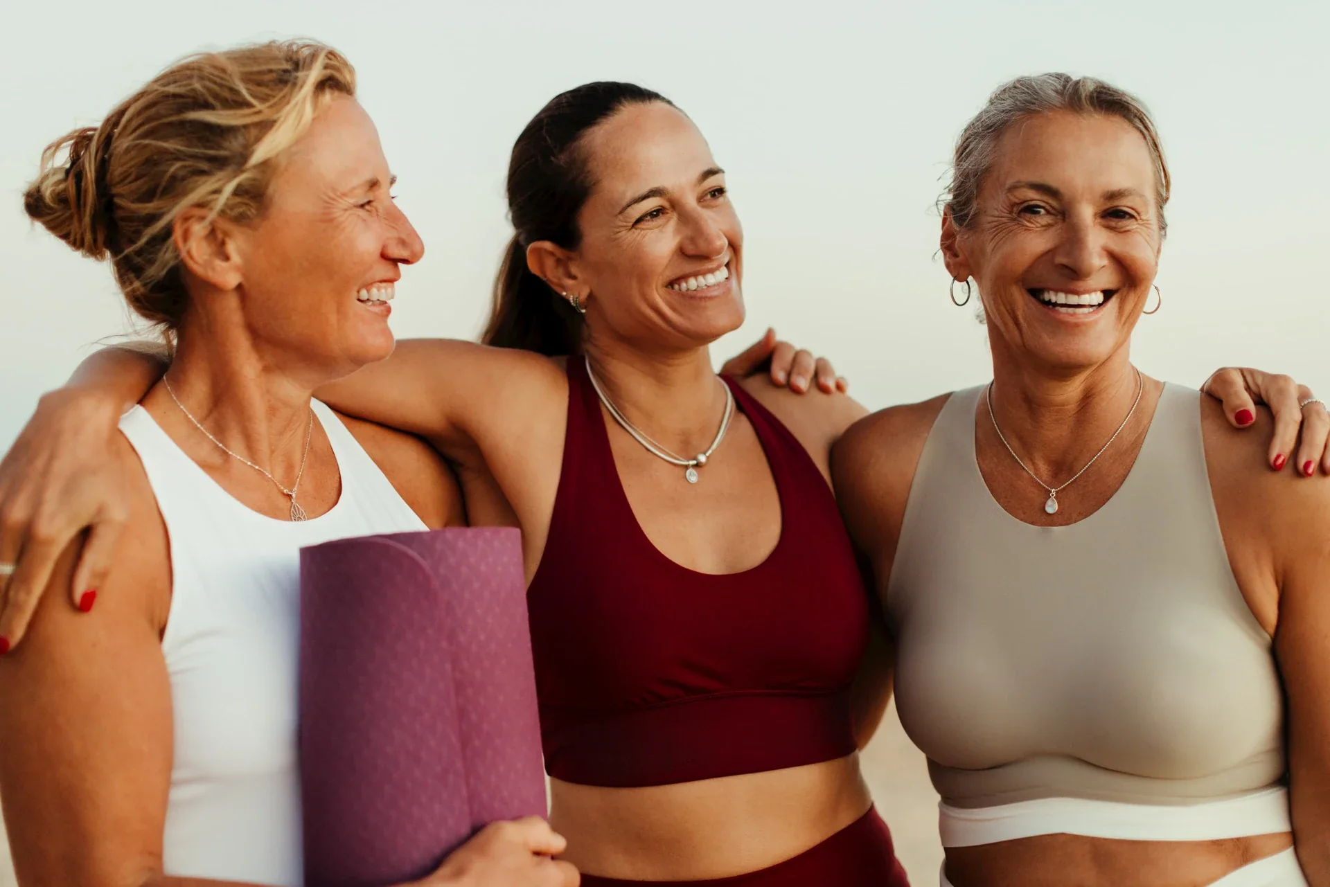 Three women in exercise clothing smiling together.